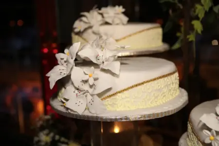 Detailaufnahme einer weißen Hochzeitstorte mit handgefertigten Zuckerrosen und goldener Verzierung